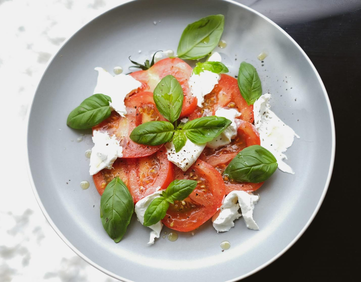 A plate of caprese salad with cheese, tomato slices, and basil leaves