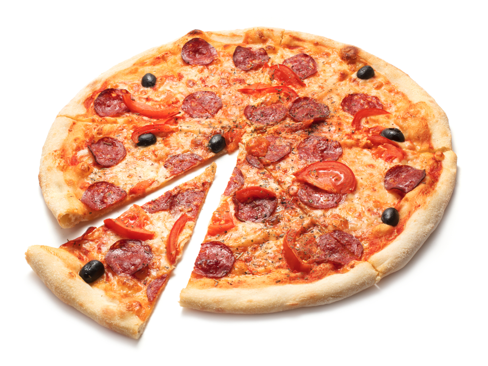 A pepperoni pizza topped with tomato slices and black olives, with one slice pulled slightly away from the whole pie on a white background.