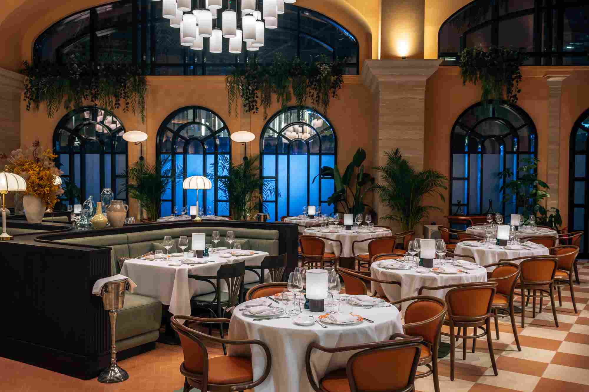 Cozy Italian restaurant room with checkered floor, set tables, and warm chandelier lighting