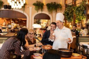 Chef serving freshly prepared Italian food to guests in a warm and elegant restaurant setting
