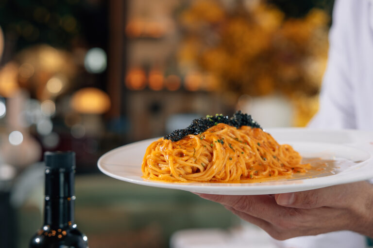 Spaghetti pasta topped with caviar, elegantly served on a plate.