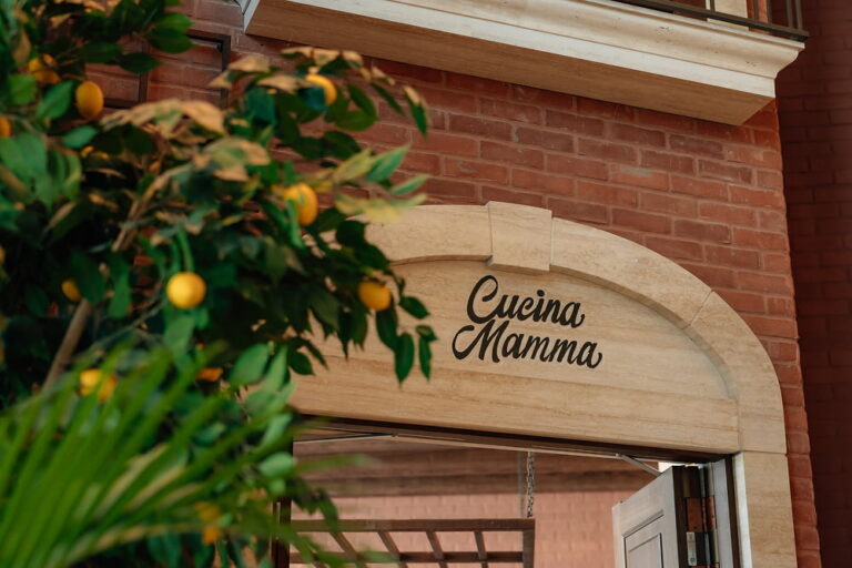 Cucina Mamma entrance at Mamabella, framed by a lush lemon tree and Italian-inspired architecture.