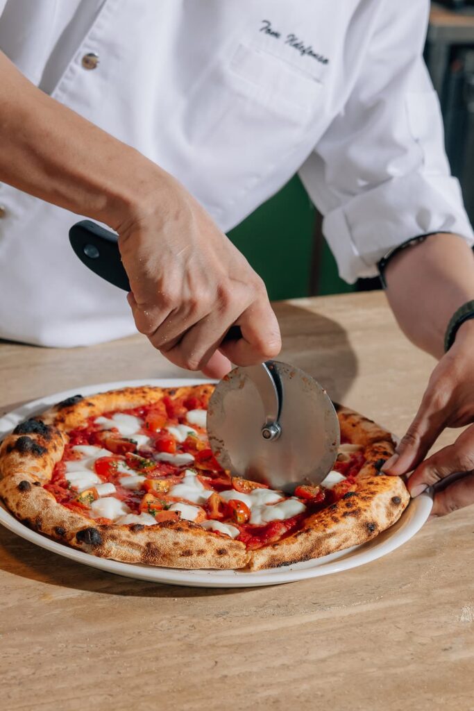 A chef cutting a pizza at Mamabella