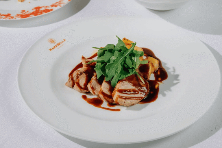 Mamabella Italian dish featuring sliced meat with rich sauce and fresh rocket.