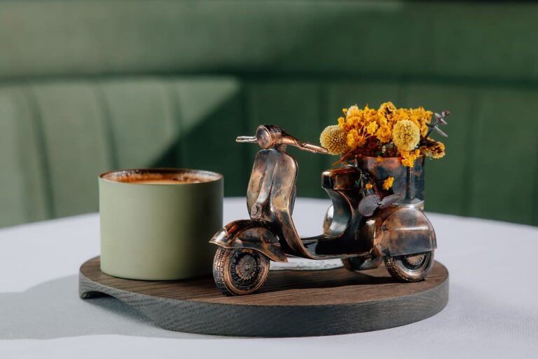 Mamabella table setting featuring a decorative vintage scooter with flowers and a coffee cup.
