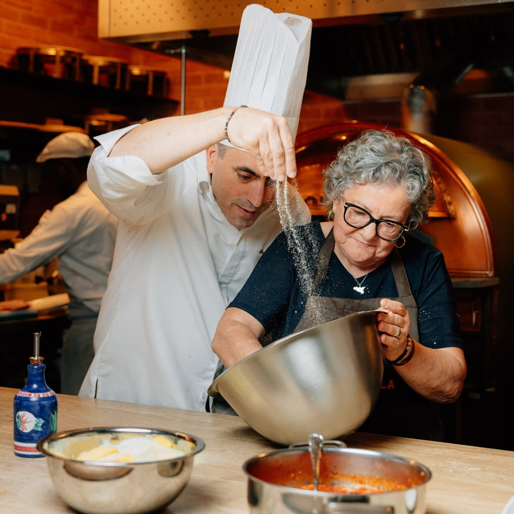 Mamabella chef and noona preparing fresh handmade pasta together in the restaurant kitchen.