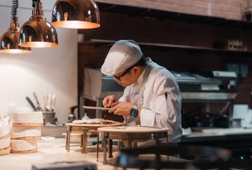 Chef plating a tasting menu course in an Italian restaurant kitchen in Dubai