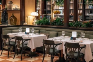 Restaurant tables set with white linen, wine glasses and polished cutlery before dinner service